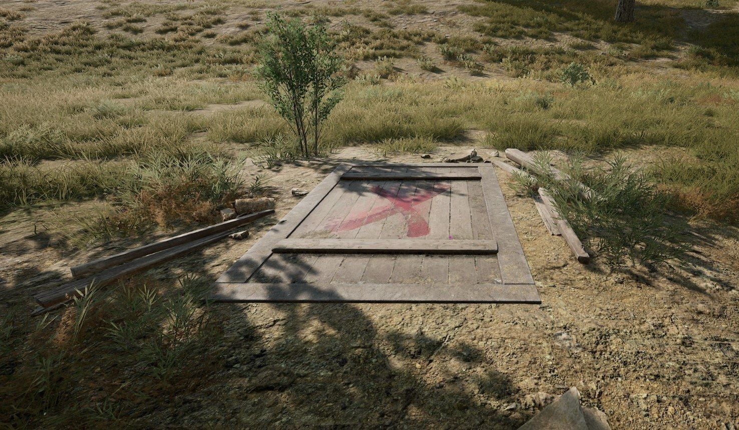 Wooden secret-room hatch with a red X on Erangel grass